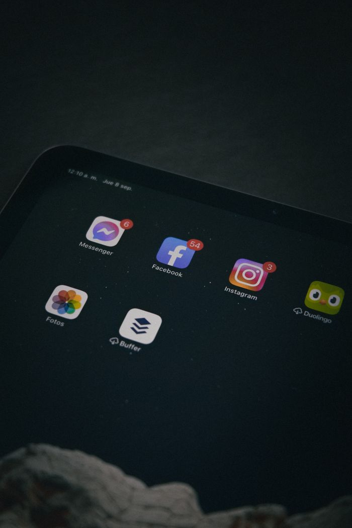 Close-up of a tablet screen displaying social media apps in a dim setting.